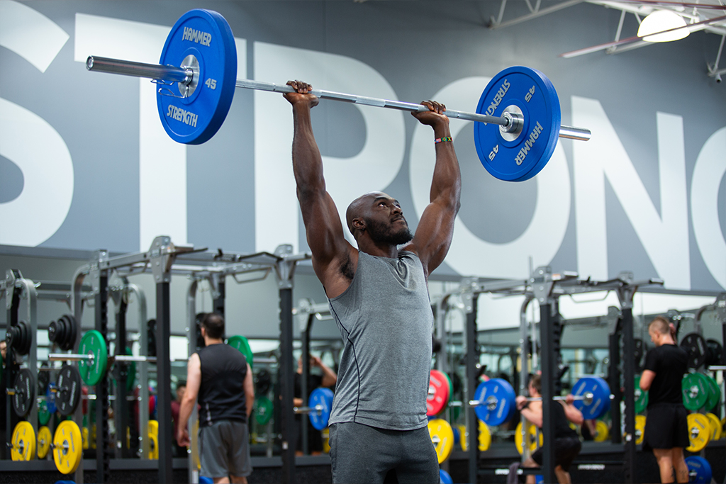 A man lifting weights above his head at a Vasa gym