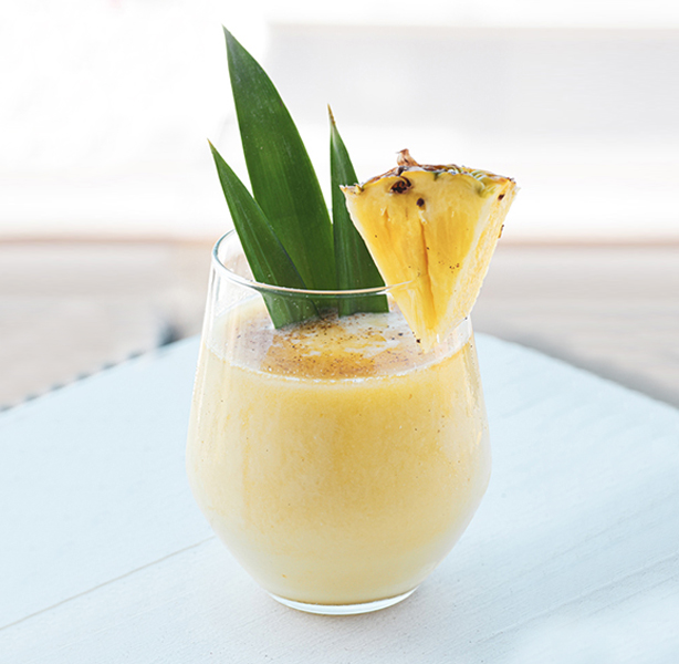 fresh pineapple juice with a pineapple wedge on the edge of the glass