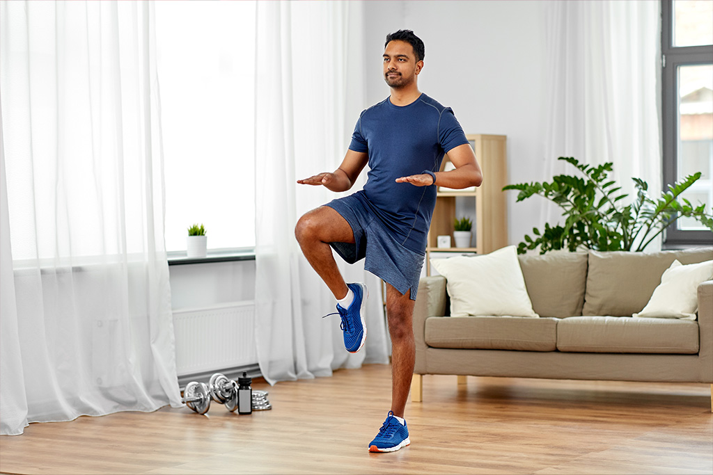 A man is working out in his Livingroom doing a light beginner cardio workout.