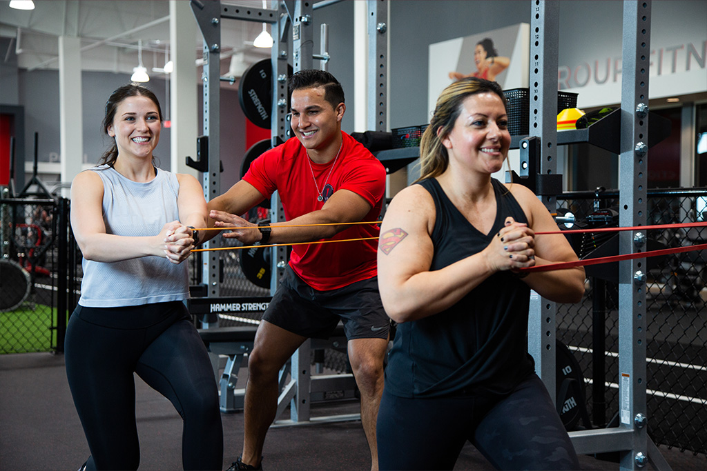 A personal trainer helping two women do core stability workouts during their private training