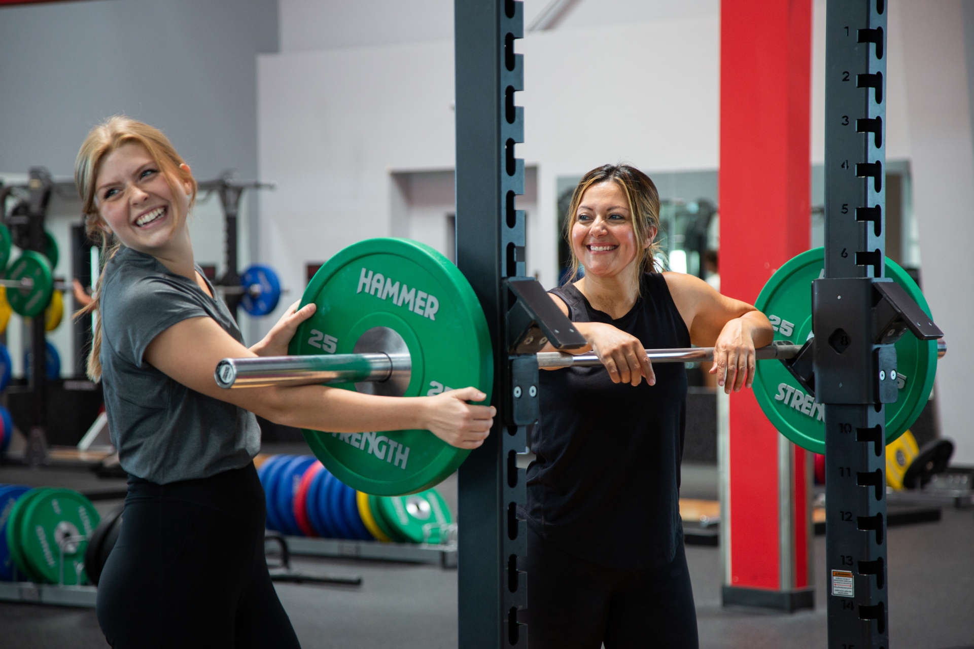 A female trainer and woman are working out at a squat rack forming good habits at Vasa