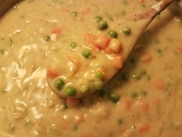 A spoon full of chicken pot pie soup.