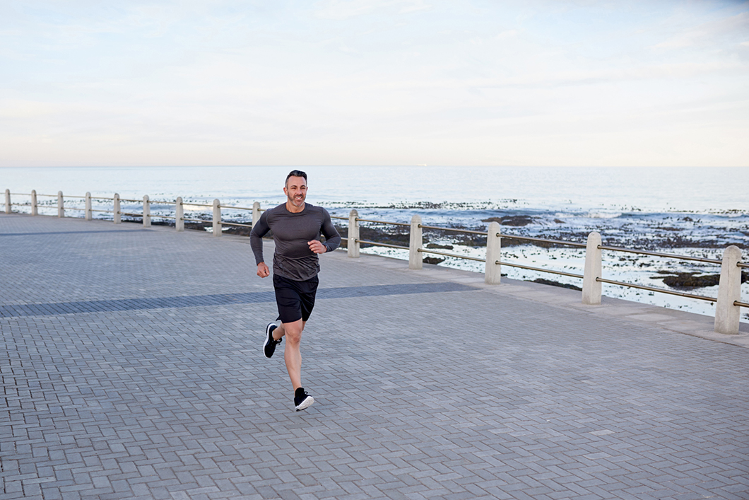 10 Must-Have Exercise Essentials For Travel, Man running by the beach when traveling