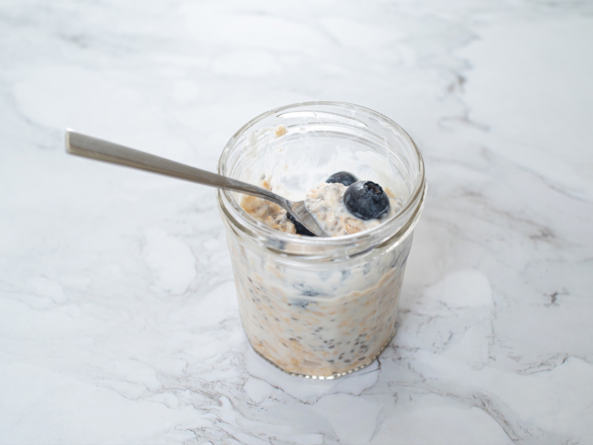 A glass full of overnight oats with blueberries