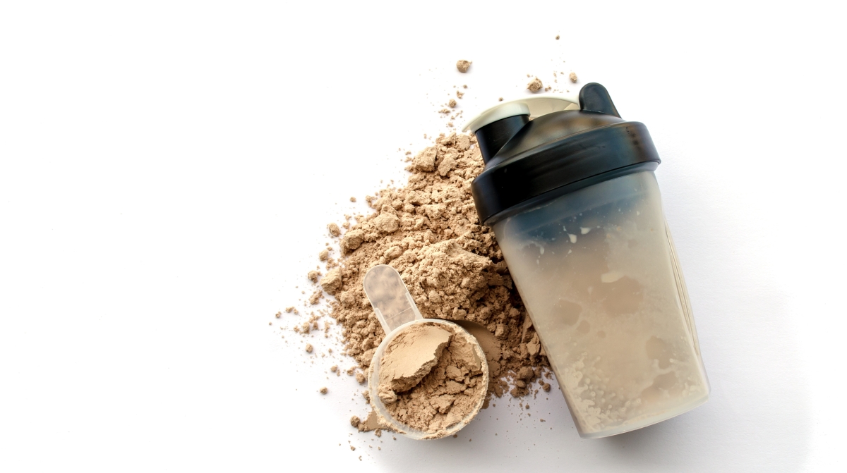 Whey protein scoop next to a mixer bottle