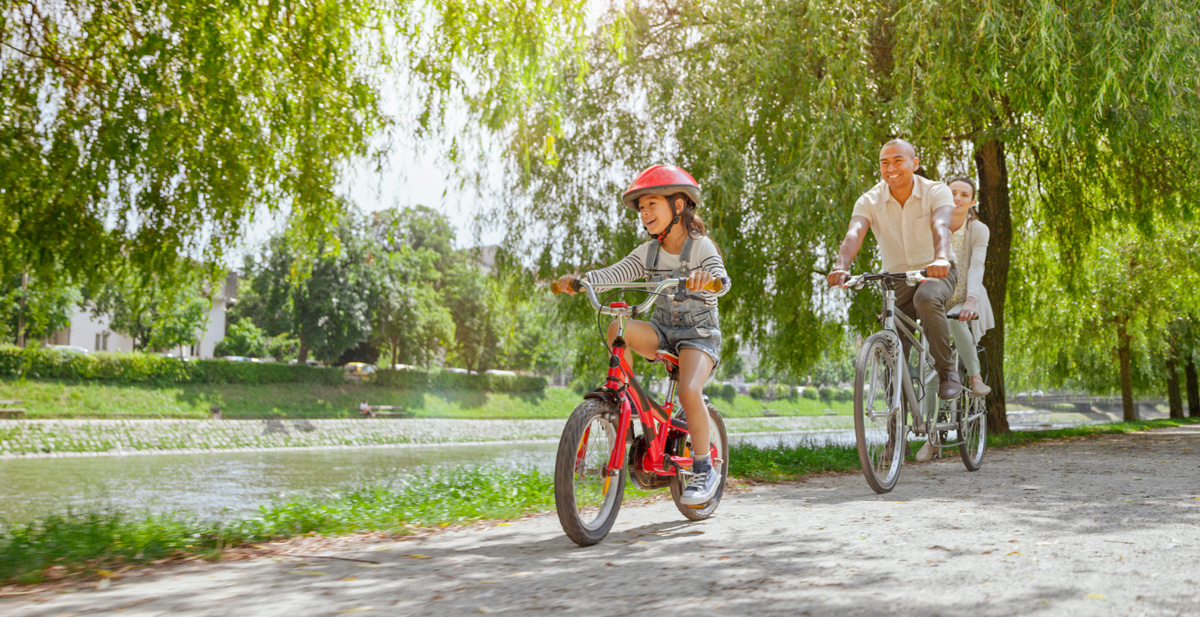 A family riding bikes together next to a river.