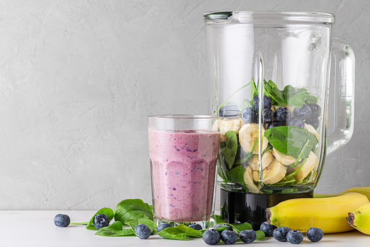 Two Mood-Boosting Smoothies, Fresh fruit and spinach in a blender next to a fresh smoothy