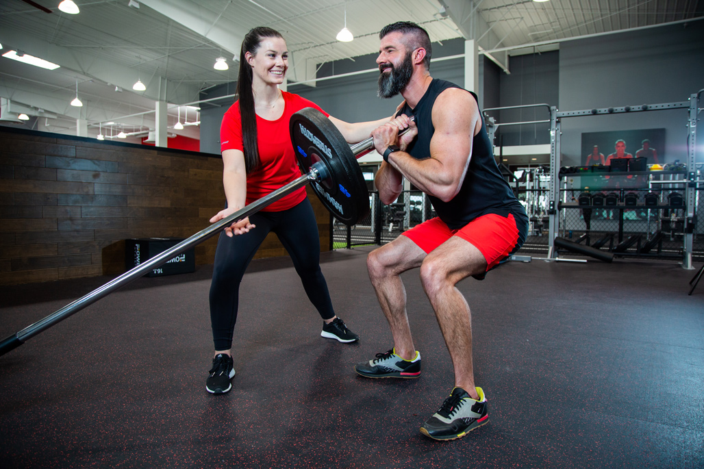 A trainer helping her client workout and meet his gym goals