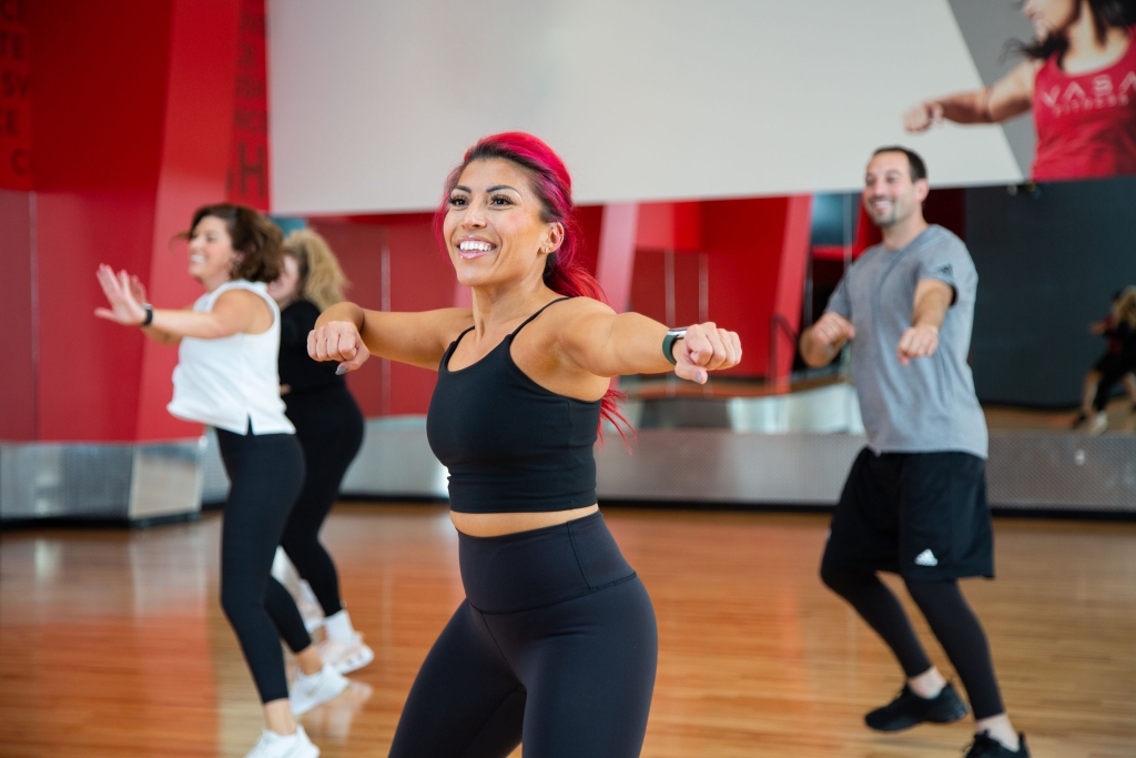 A group of people smiling while in their group fitness class. How to Choose The Best Group Fitness Class