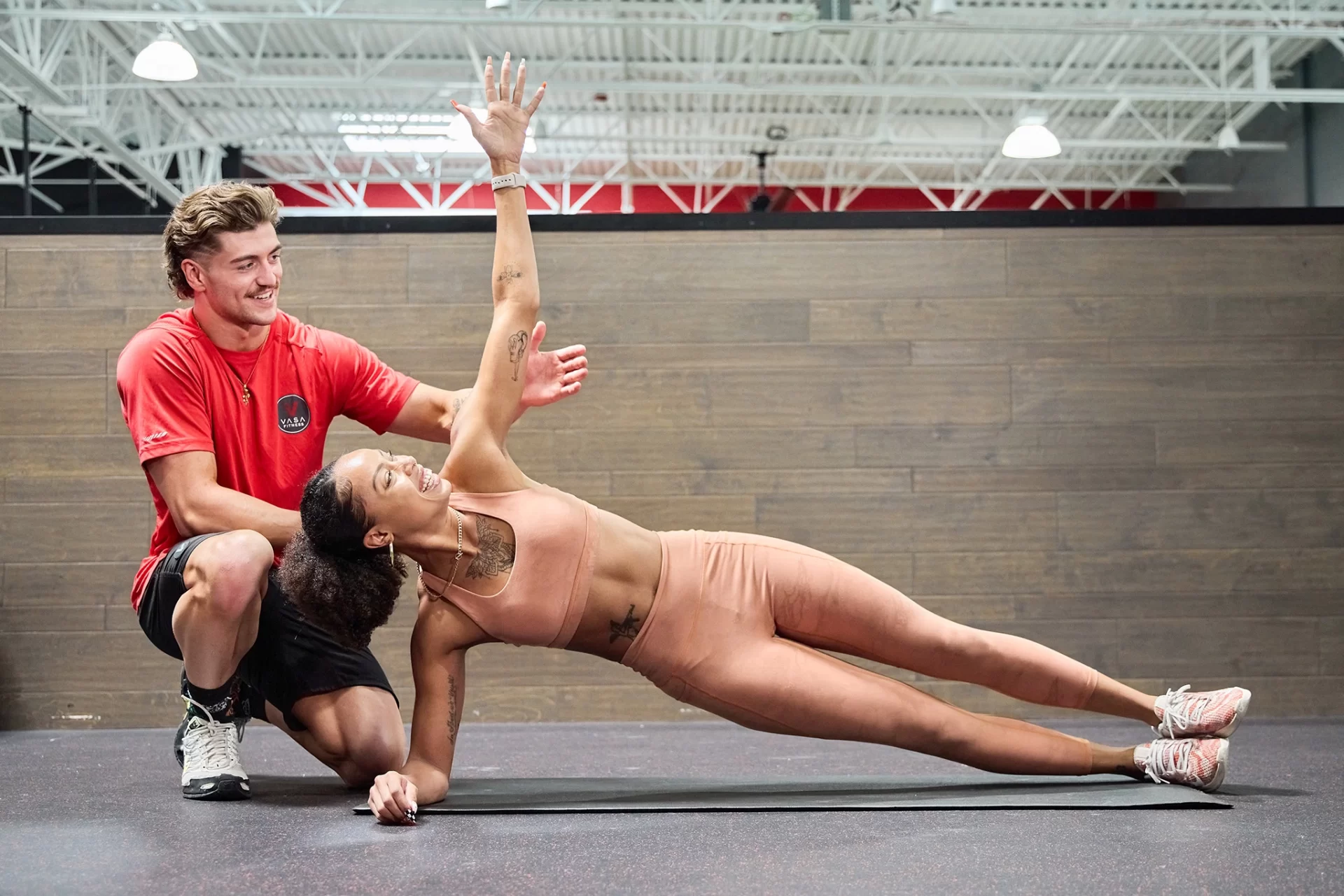 Female athlete with male personal trainer doing stretches at VASA Fitness