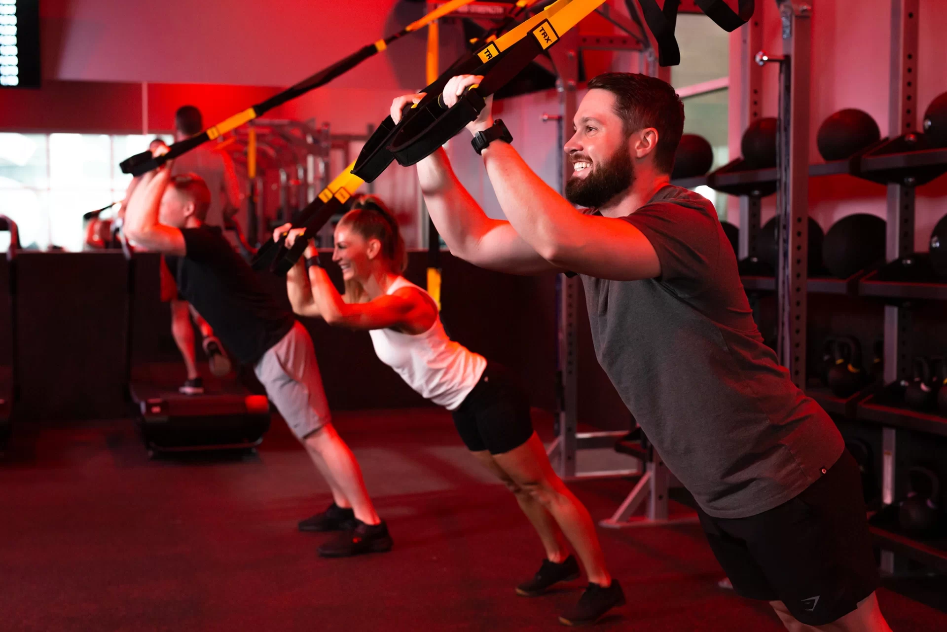 Athletes in STUDIO RED HIIT class exercising with TRX at VASA Fitness