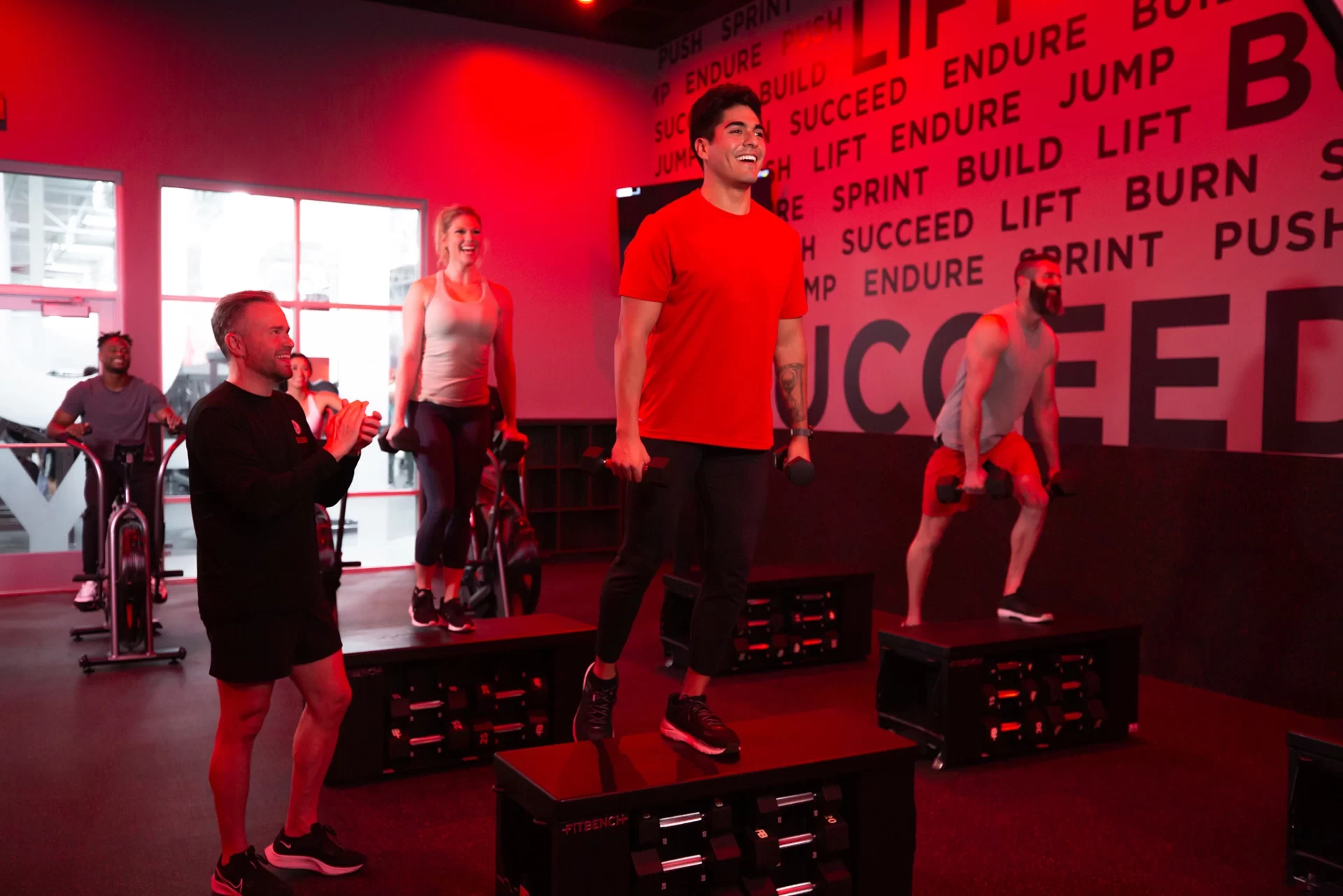 Athletes doing steps with dumbbells exercise in STUDIO RED HIIT class at VASA Fitness