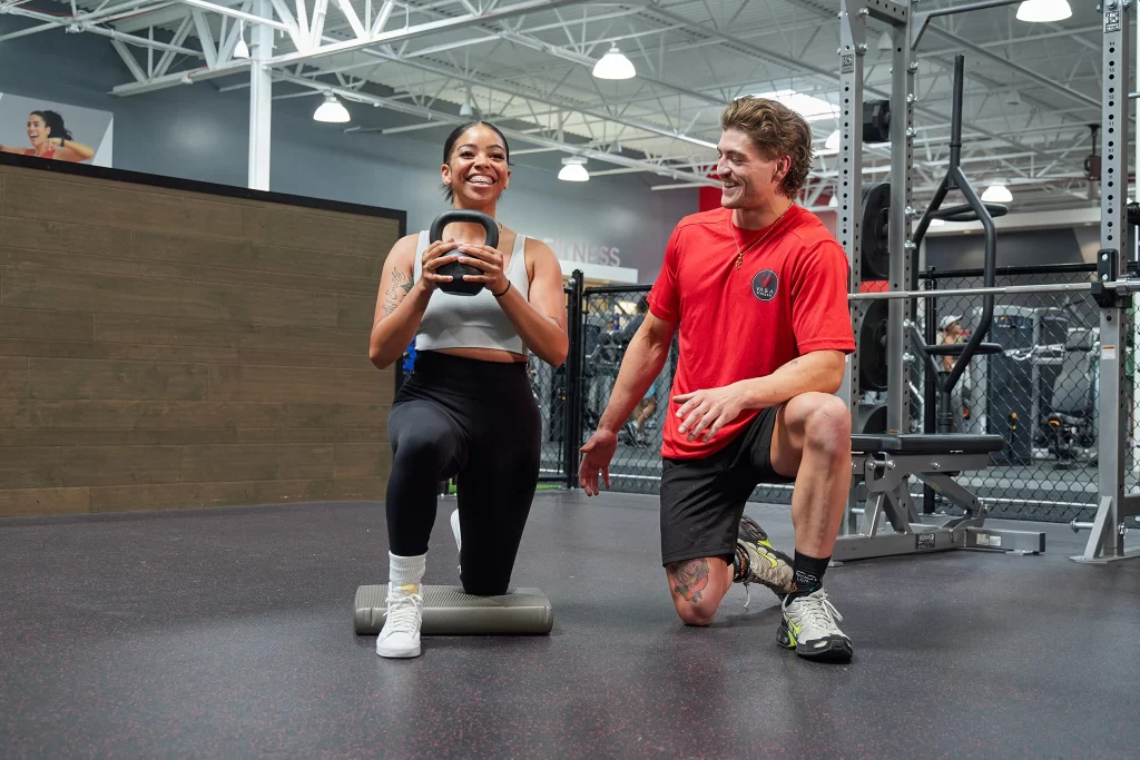 Female athlete doing a kettlebell workout with a male personal trainer at VASA Fitness