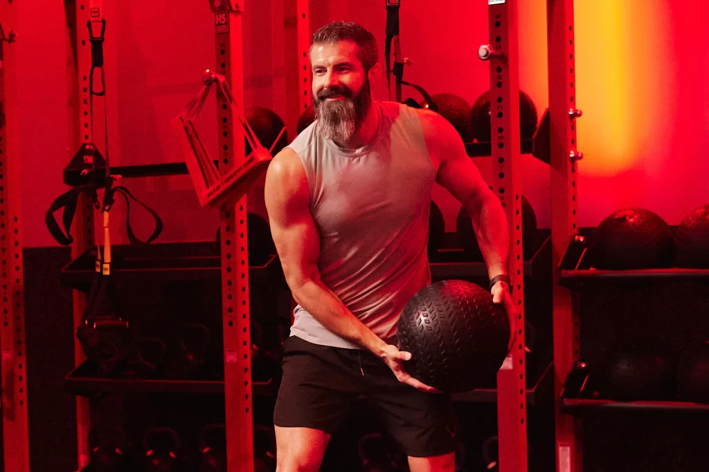 Male athlete doing a workout with a medicine ball in a VASA Fitness Group STUDIO RED HIIT class