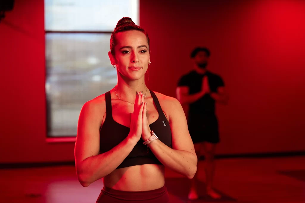 Female athlete doing yoga stretches in a group STUDIO FLOW Infrared Yoga class at VASA Fitness