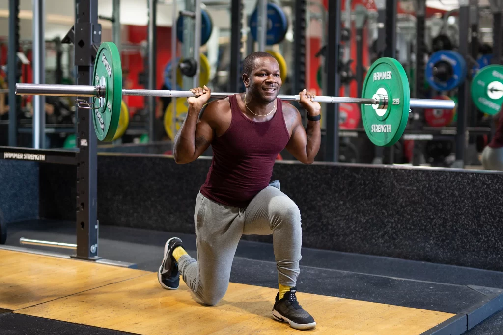 Male athlete doing strength training lunge squats with a barbell at VASA Fitness