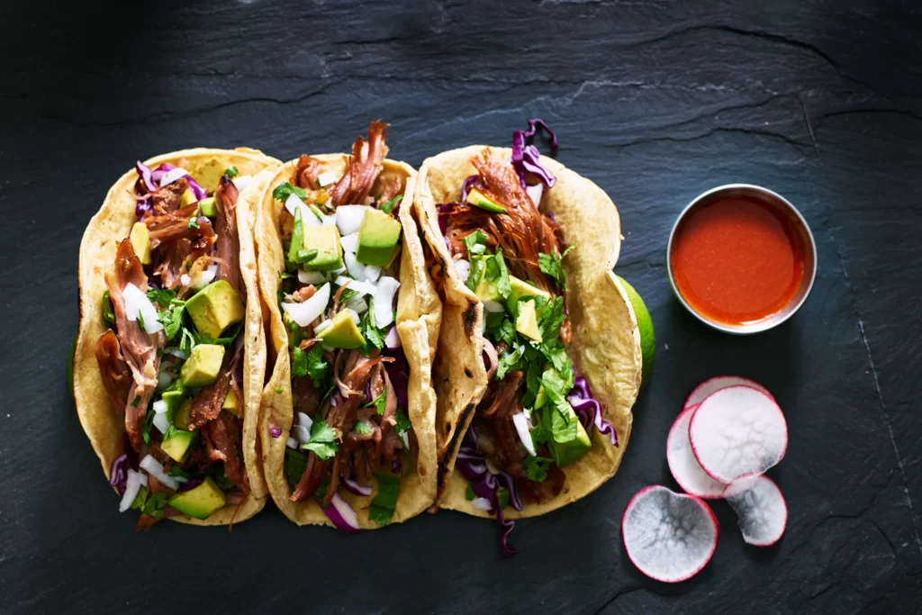 A group of tacos loaded with lettuce, meat, and other vegetables